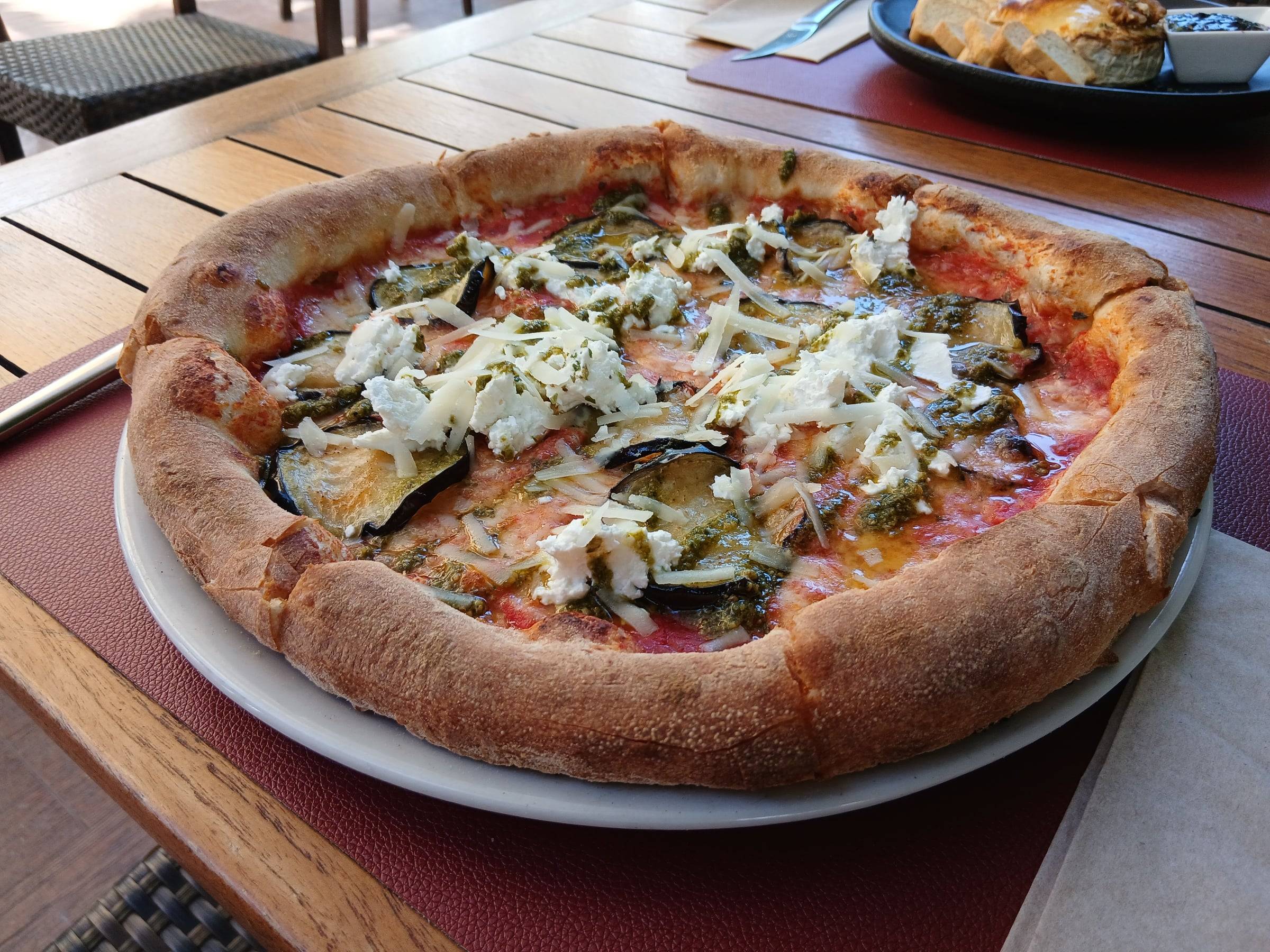 Pizza de berenjena con pesto y queso fresco, recién salida del horno de leña